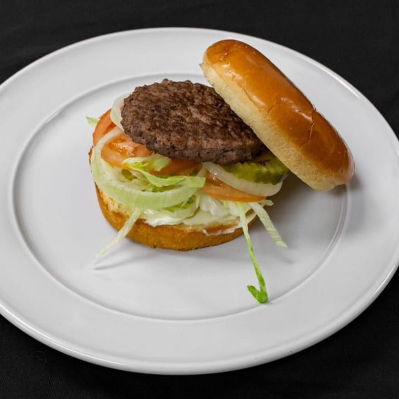 A Mother & Daughter Kitchen burger with a beef patty, lettuce, tomato, onion, and pickles.