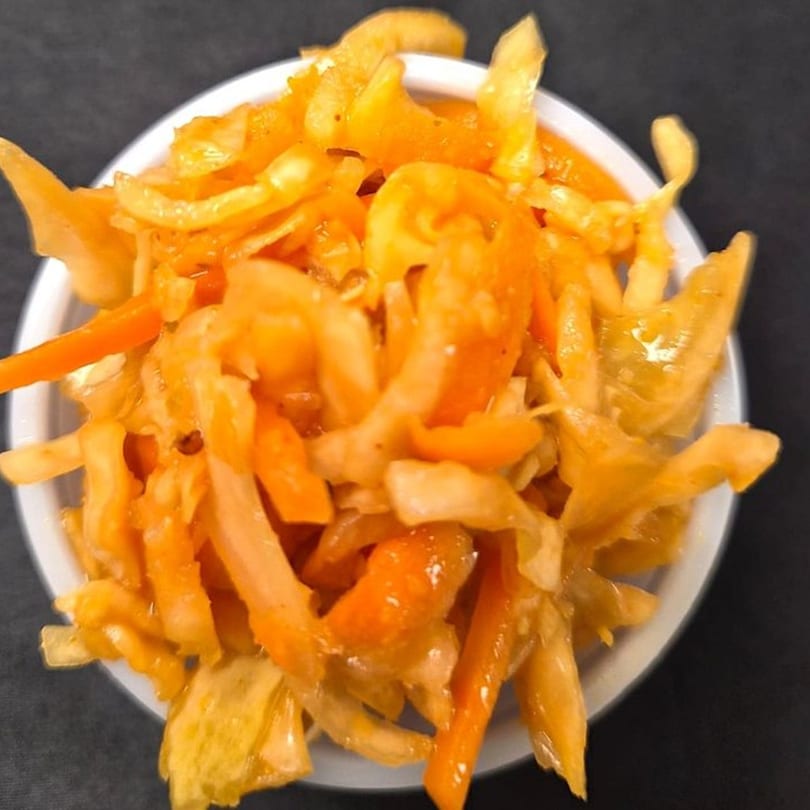 Close-up of a white bowl filled with Mother & Daughter Kitchen's orange pickled vegetables.